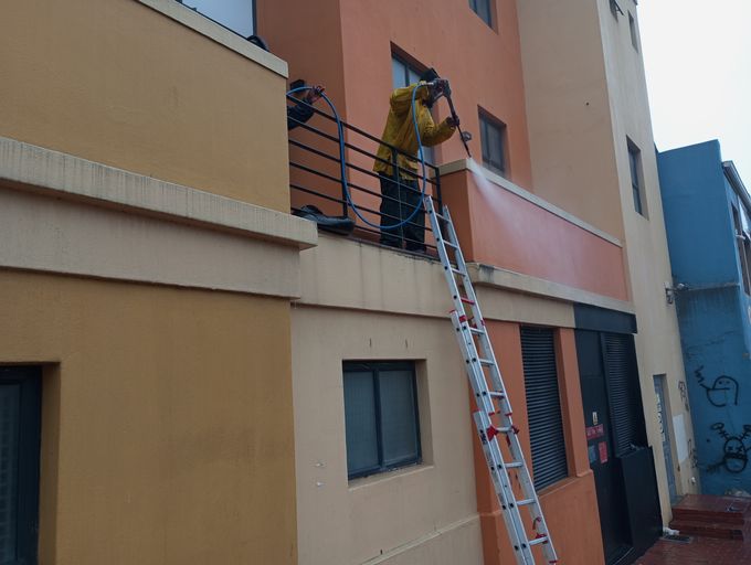 Multi-storey exterior wall pressure cleaned from a ladder, Cape Town